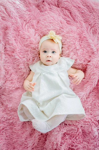 Foto de una adorable niña caucásica acostada en la cama y sonriendo. Ella está mirando directamente a la cámara . — Foto de Stock