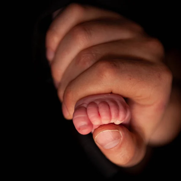 Otec drží nohu své novorozené dcery — Stock fotografie