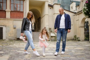 Küçük bir kızı olan iki ebeveyn eski şehrin sokaklarında yürüyor..