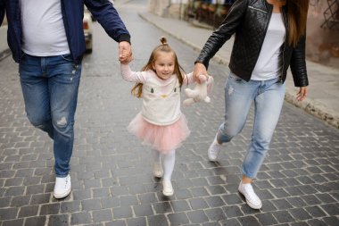 Küçük bir kızı olan iki ebeveyn eski şehrin sokaklarında yürüyor..