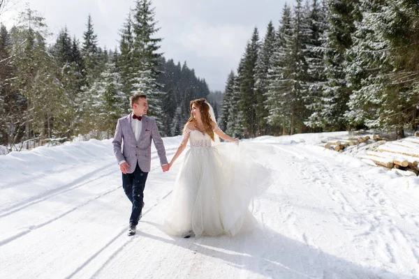 新娘和新郎在冬季森林的背景下走在一起 Snowing — 图库照片