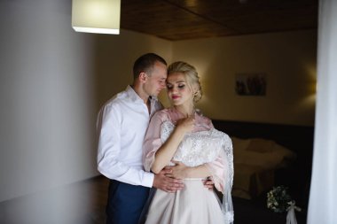 İpek bornozlu gelin elbisesini deniyor. Nişanlısı tarafından kucaklanıyor. Gelin ve damat düğün için hazırlanıyorlar..