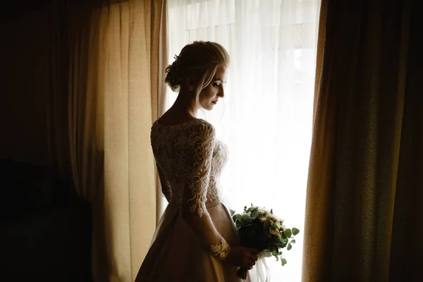 Bride and groom in a hotel room. The groom hugs and kisses the bride in the neck.