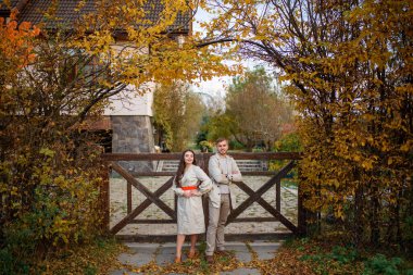 Kır evinin önünde dikilen bir çiftin tam boy portresi.