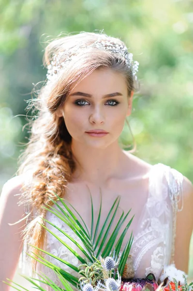 Pembe gelinlikli mutlu gelin. Kız elinde bir düğün buketi tutuyor. Ormanda Boho tarzı bir düğün töreni..