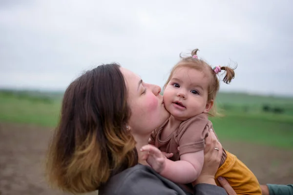 Mom kisses her daughter on the cheek. Close-up.