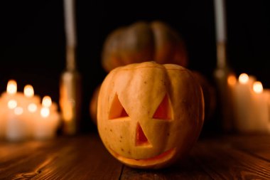 Cadılar Bayramı balkabağı arka planda mumlar ve siyah bir arka plan.