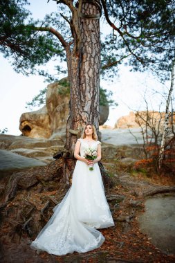 Güzel sarışın gelin elinde bir buket çiçek tutuyor..