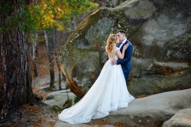 Gelin ve damat kayaların arkasında birbirlerine sarılıyorlar..