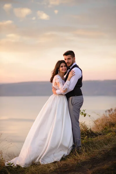 Nevěsta Ženich Objímají Pozadí Jezera Během Západu Slunce — Stock fotografie