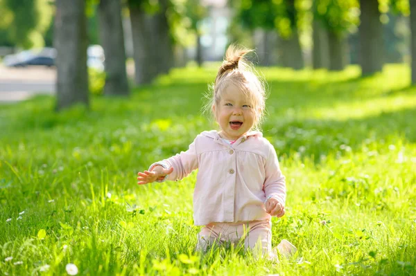 普段着のかわいい女の子が緑の芝生の上に膝の上に座っている 女の子は怖がってる — ストック写真