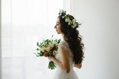 Bir buket çiçekli ve başında çelenk olan güzel bir gelin..