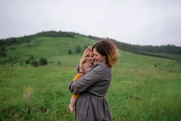 Mama Trzyma Swoją Córeczkę Ramionach Strzał Tle Zielonych Wzgórz — Zdjęcie stockowe