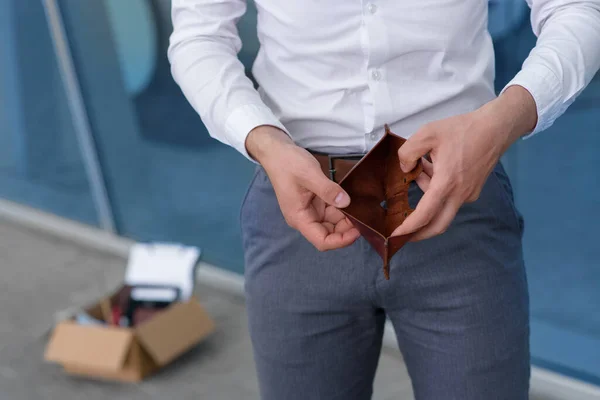 A fired employee due to the crisis opens showing his empty wallet.