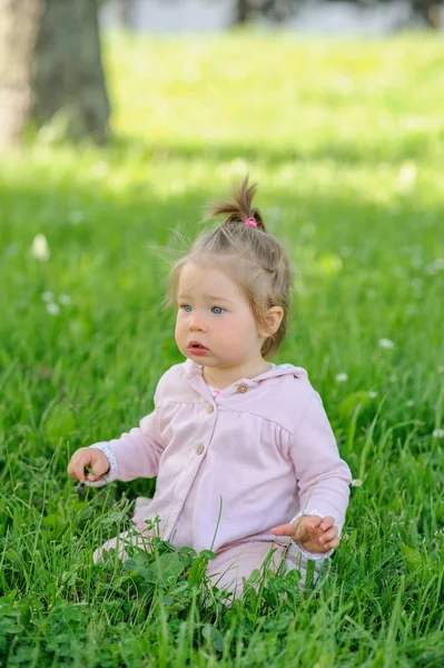 穿着休闲装的可爱小女孩跪在绿草上 — 图库照片