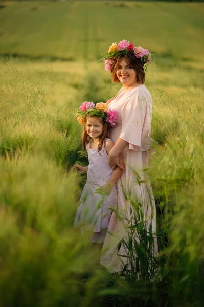 Yeşil Buğday Tarlasında Pembe Elbiseli Anne Kız Başlarının Üstünde Çiçek — Stok fotoğraf