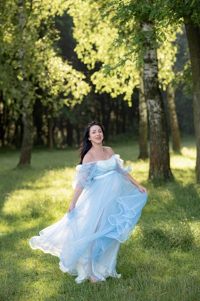 緑の木の背景に青いドレスを着た妊婦 — ストック写真