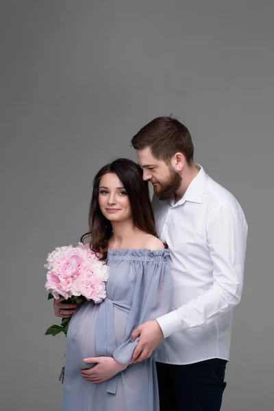 Eine Schwangere Frau Und Ihr Mann Umarmen Sich Vor Grauem — Stockfoto