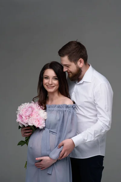 Eine Schwangere Frau Und Ihr Mann Umarmen Sich Vor Grauem — Stockfoto