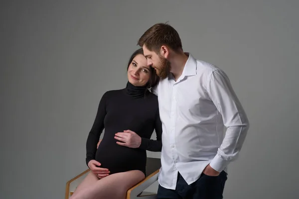 Hamile Bir Kadın Kocası Gri Bir Arka Planda Sarılıyorlar Bebek — Stok fotoğraf