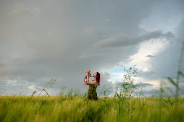 Bir anne üç aylık oğlunu nazikçe bir buğday tarlasında kollarına alır..