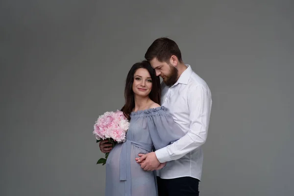 Eine Schwangere Frau Und Ihr Mann Umarmen Sich Vor Grauem — Stockfoto