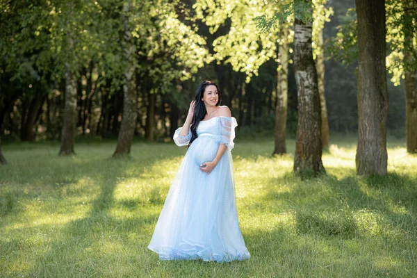 Zwangere Vrouw Poseren Een Blauwe Jurk Een Achtergrond Van Groene — Stockfoto