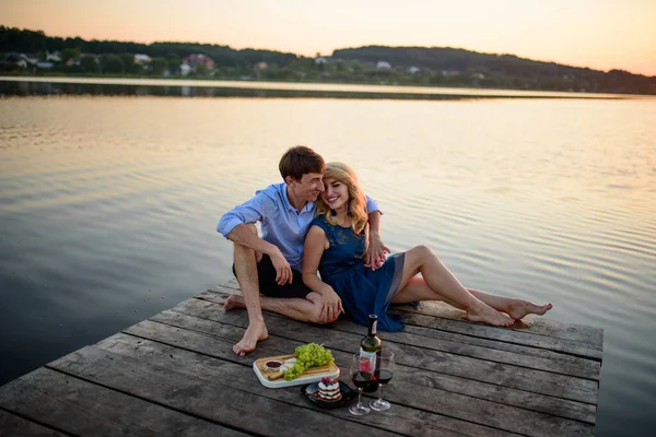 男人和女人在湖边的码头野餐 — 图库照片