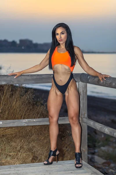Fitness-Mädchen posiert mit einem schönen schwarz-orangen Bikini — Stockfoto