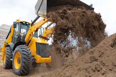 Excavator machine unloading sand during earth moving works clipart