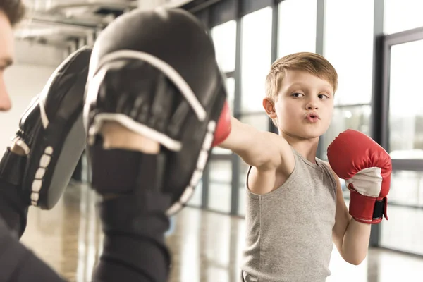 Petit boxeur enfant pratiquer des coups de poing avec l'entraîneur à la salle de gym — Photo de stock