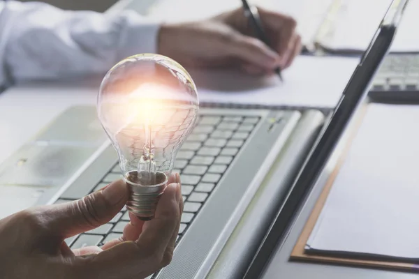 Männliche Hand Hält Eine Glühbirne Und Benutzt Einen Laptop Für — Stockfoto