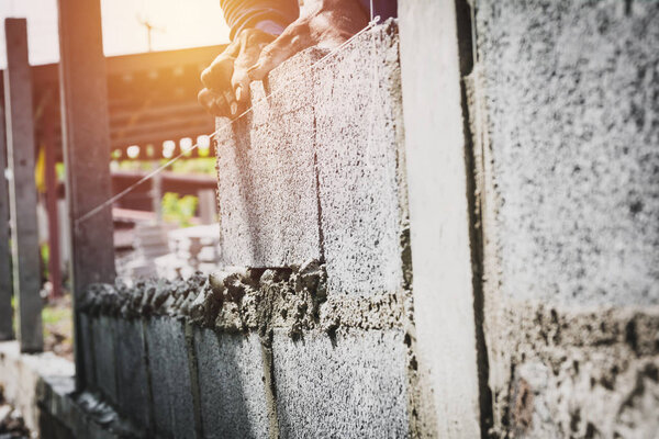 Worker with block concrete cement mortar wall at construction site.