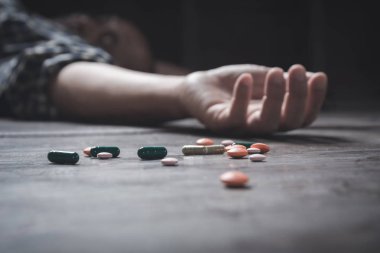 The man committing suicide by overdosing on medication. Close up of overdose pills and addict. clipart