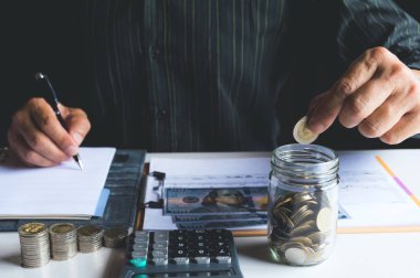 Cam kavanoza para koyuyorsun. Tasarruf, mali ve muhasebe kavramı.