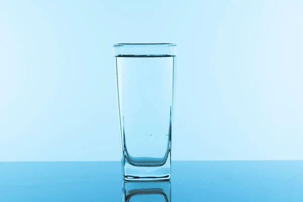Water glass on blue background. Glass with clean drinking water.