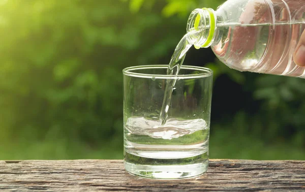 Hembra Mano Verter Agua Botella Vidrio Sobre Fondo Naturaleza — Foto de Stock