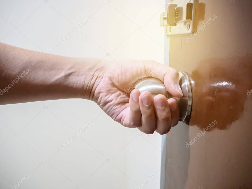 Close up of hand holding a door knob, opening or closing the door.