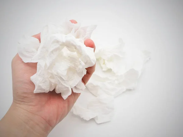 Hand holding a tissue paper and pile of tissue paper on a white background.