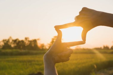 Gün batımı ile çerçeve hale eller. Çerçeve jest yapma kadın elinde yakın çekim.