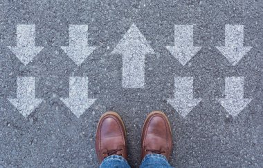 Üstten görünüm oklarla işaretlenmiş bir yol seçerek ayakkabı giyen adam. Doğru yolu kavramı seçer.
