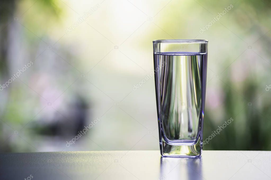 Water in the glass on table with nature background