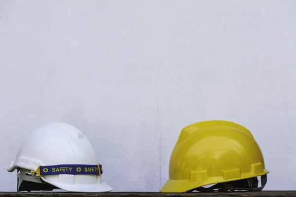 Construction Helmet, yellow and white safety helmet on wooden table.