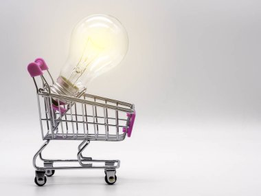 Ampul beyaz arka planda, alışveriş arabasında. Enerji ve iş kavramı kaydediliyor.