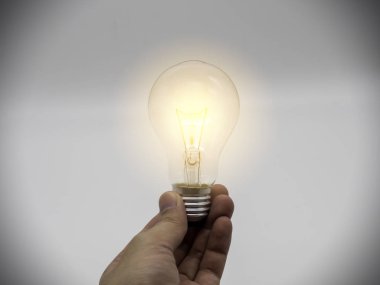 Doğa arka planında parıldayan ampullerle el ele tutuşmak. Fikir, yaratıcılık ve ampul kavramı ile enerji tasarrufu.