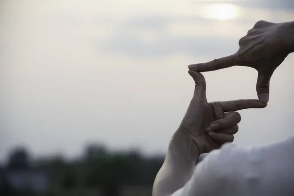 Hands making frame with sunset. Close up of woman hands making frame gesture.