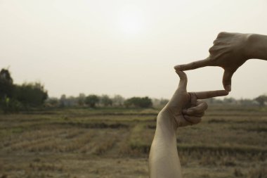 Gün batımı ile çerçeve hale eller. Çerçeve jest yapma kadın elinde yakın çekim.
