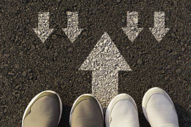 Üstten görünüm Beyaz oklarla işaretlenmiş bir yolu seçme beyaz ayakkabı giyen adam. Doğru yolu kavramı seçer.