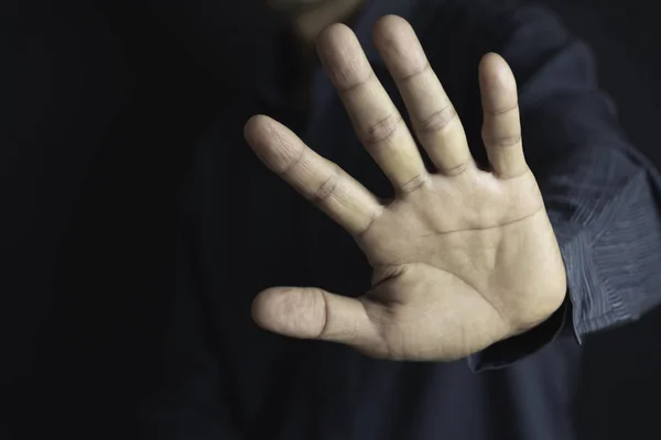 Show hand with stop gesture on black background. Man showing sto
