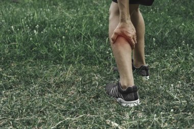 Bir adam kötü bir bacağına tutunur. Bacağındaki ağrı. Sağlık ve painf